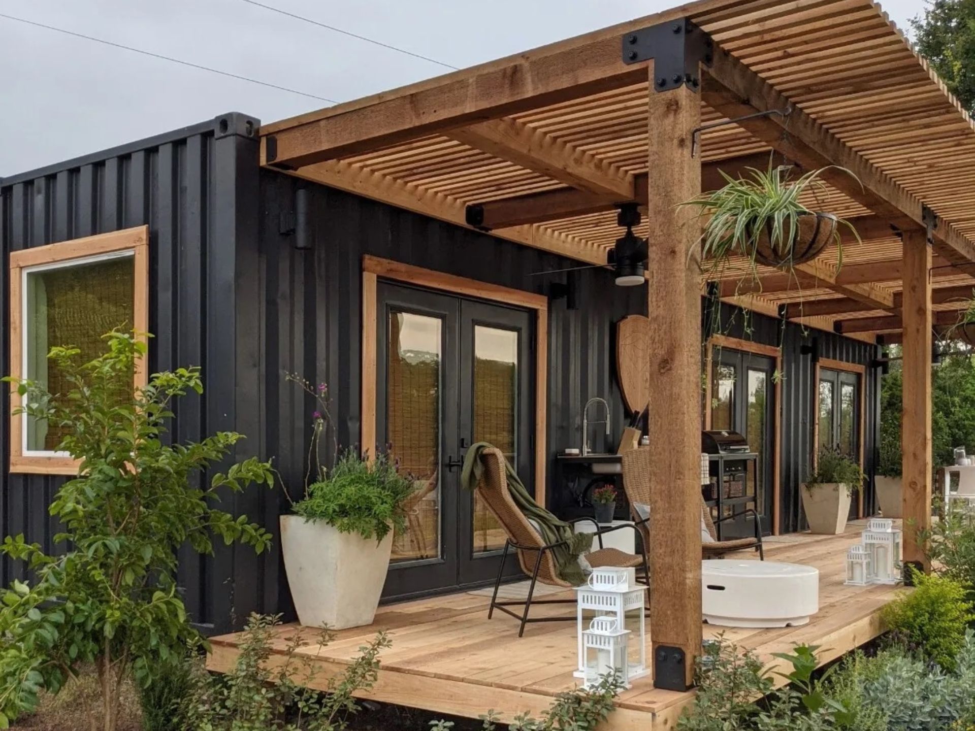 Black Joshua container home with a beautiful small wooden porch in front of it