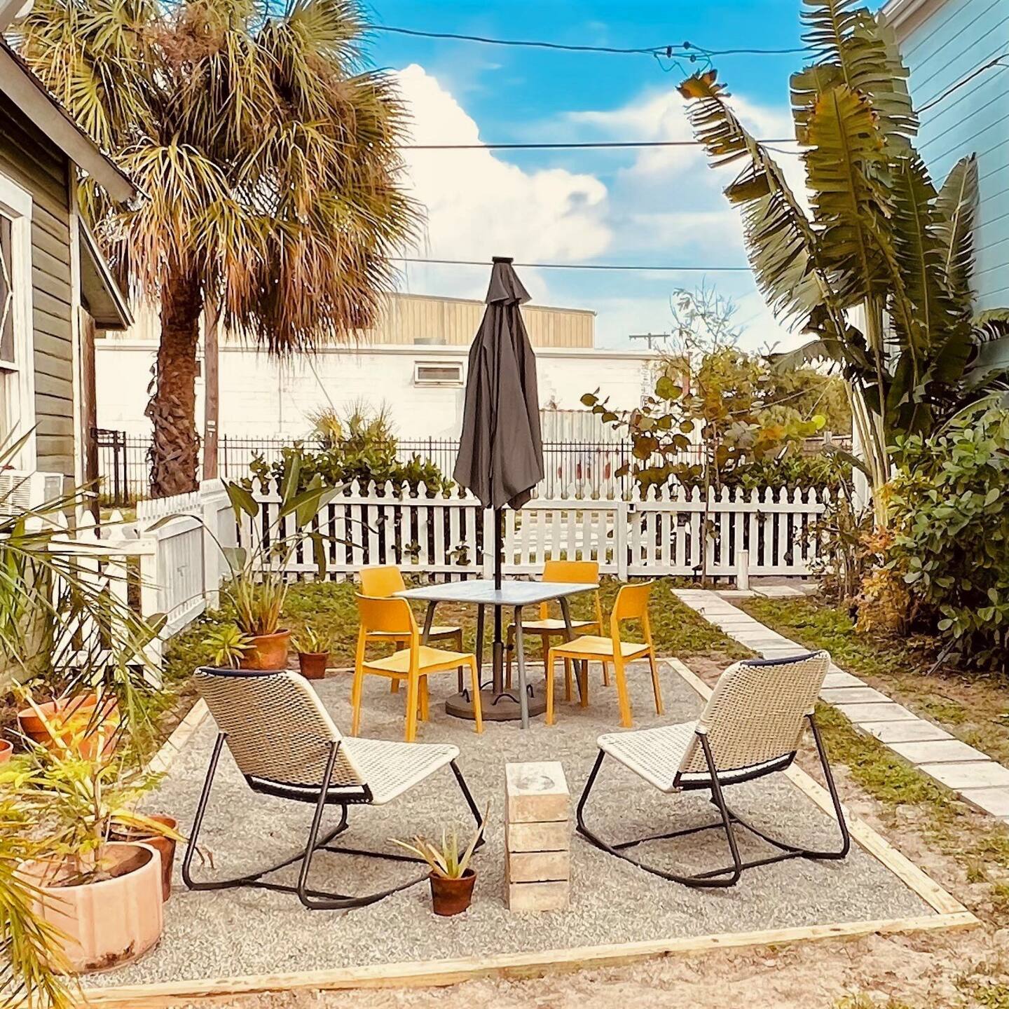 Backyard with palm trees and four yellow chairs, on the sand