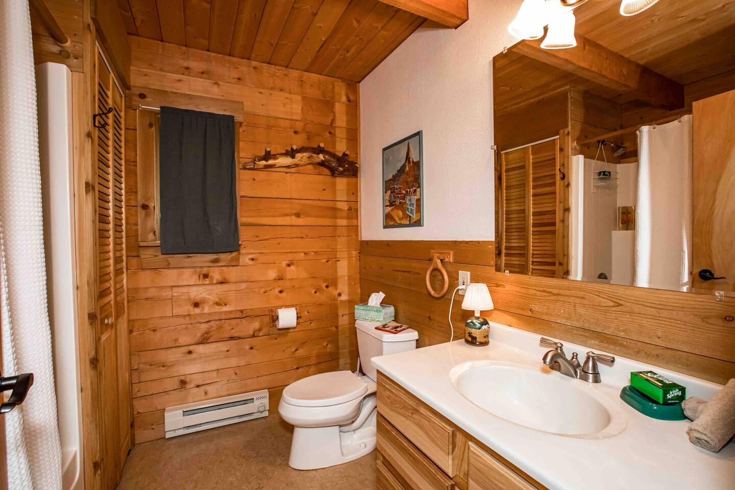 Bathroom made all of wood, with a large mirror and white sink