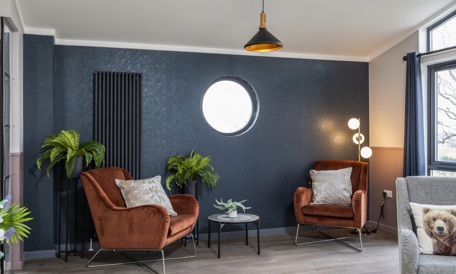 Two brown plush armchairs in front of a dark blue wall