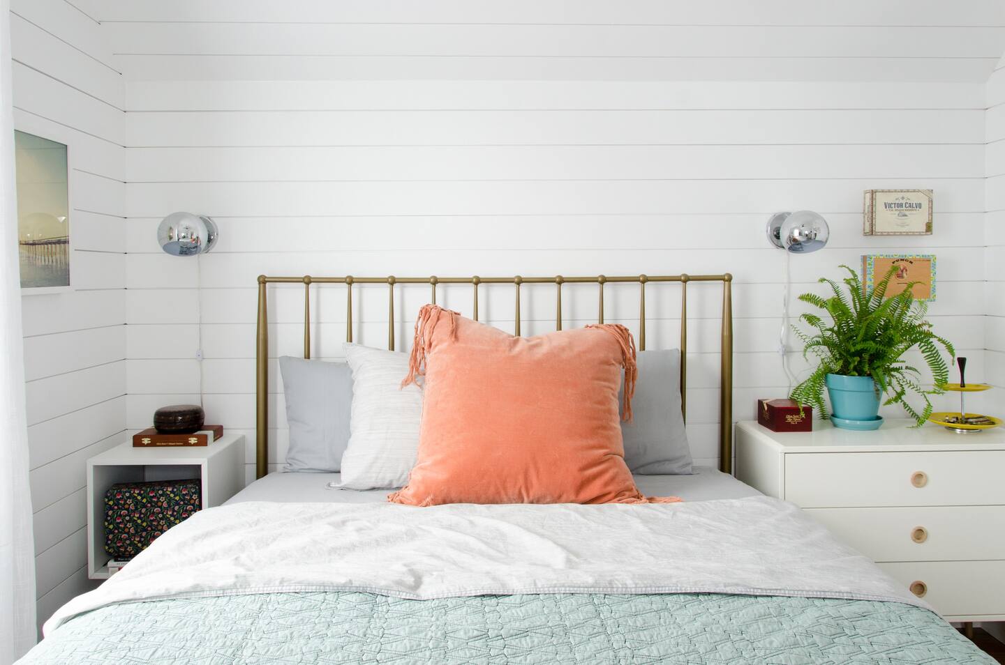 Cozy bed in the middle of small bedroom with a great pillow in the color of peach