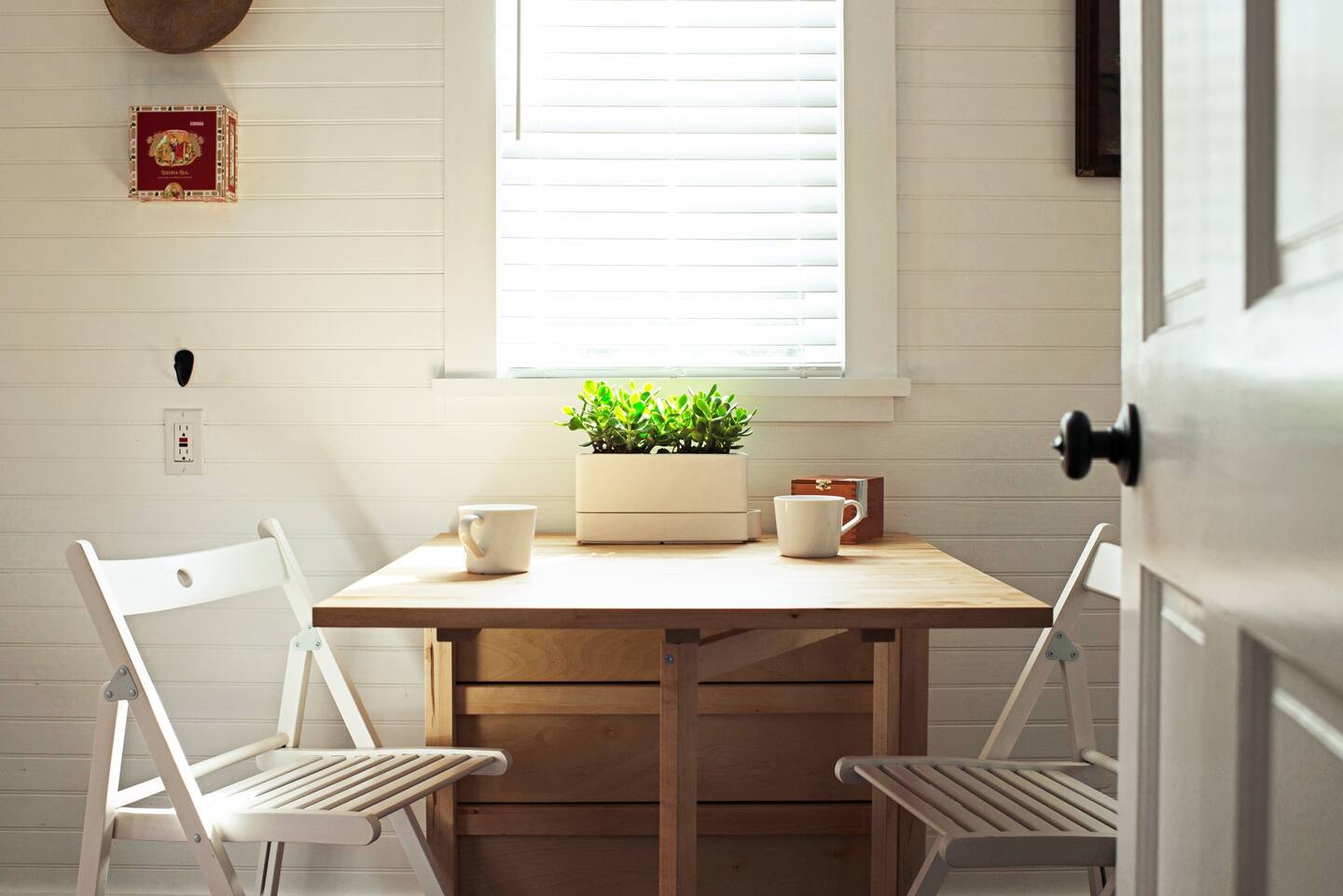 Dining room in the small kitchen with two white chairs and small wooden desk