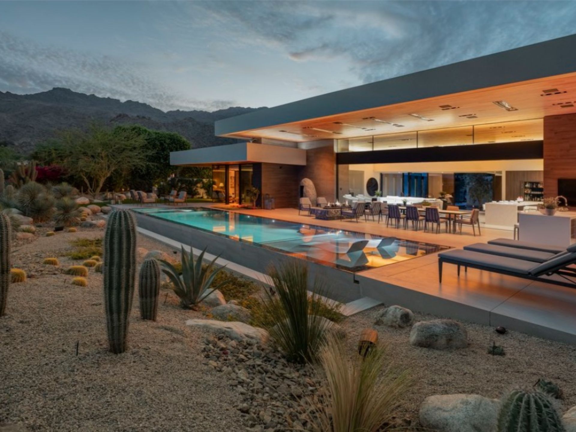 backyard of a modern house set in a desert, has a pool and a dining table