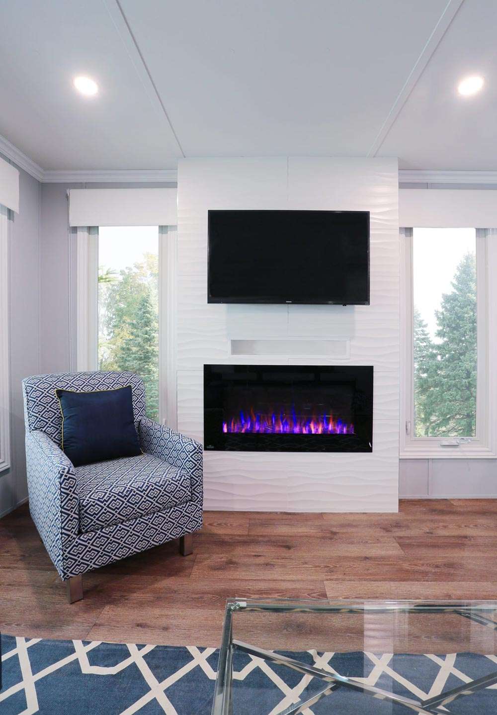 Fireplace wit a TV above and white-blue armchair on the left
