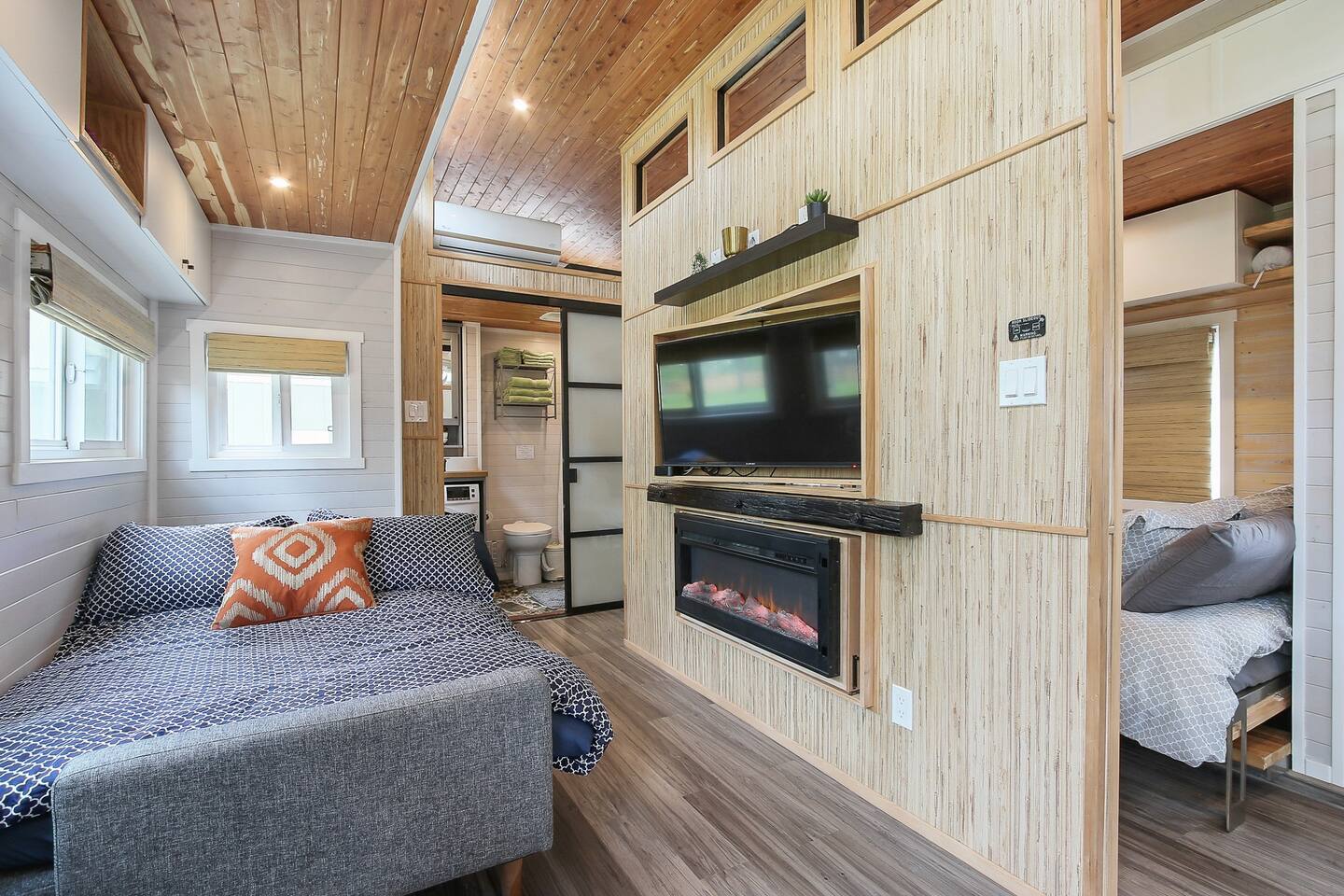Pull out couch in living room, and  fireplace and TV on wooden wall near bed