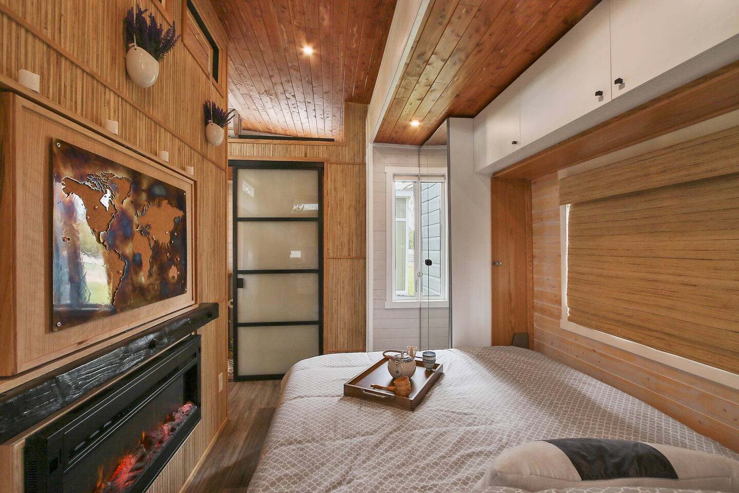 Cozy bed near wooden wall with fireplace and world map on it