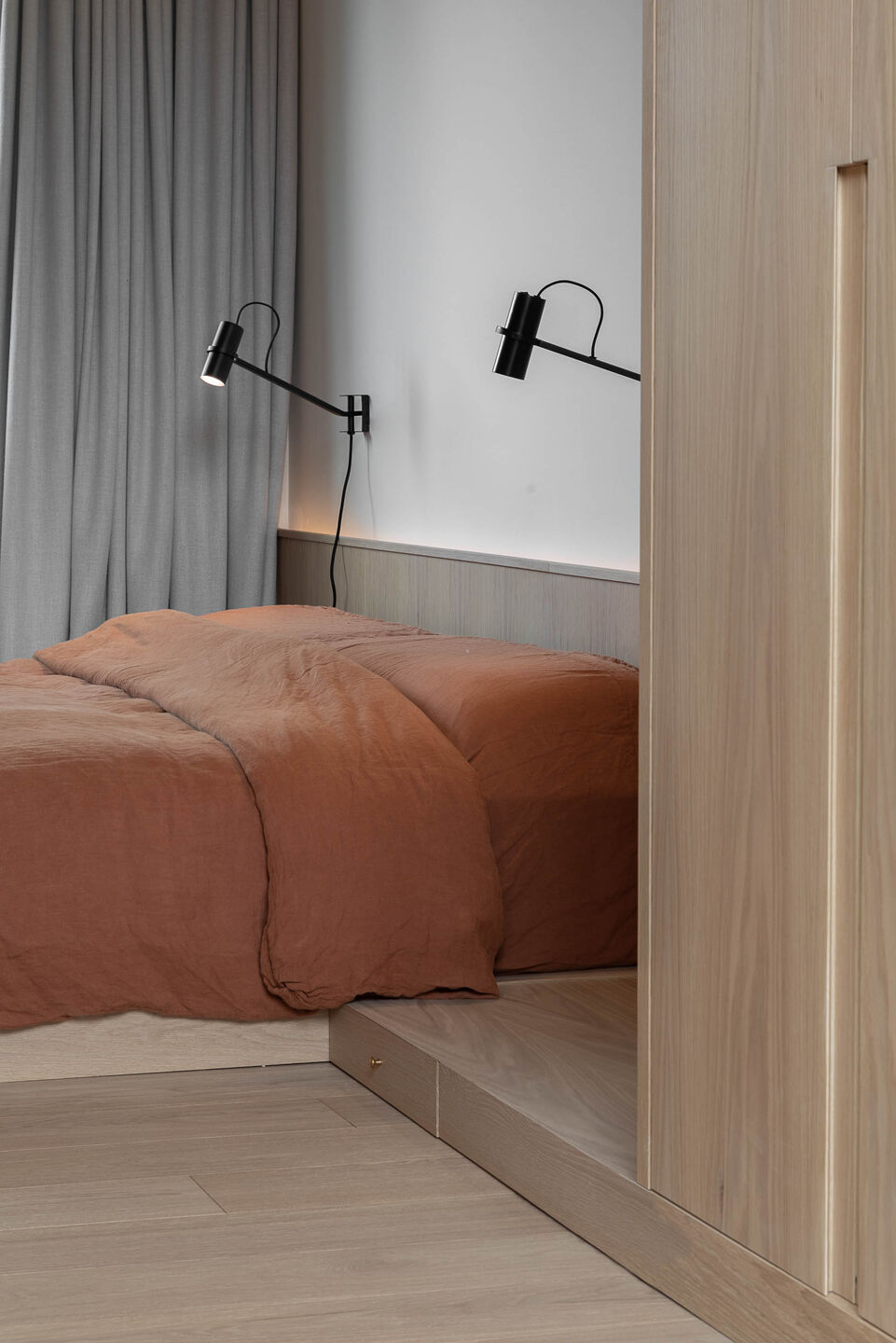Master bedroom with orange sheets, large bed and two black lamps above