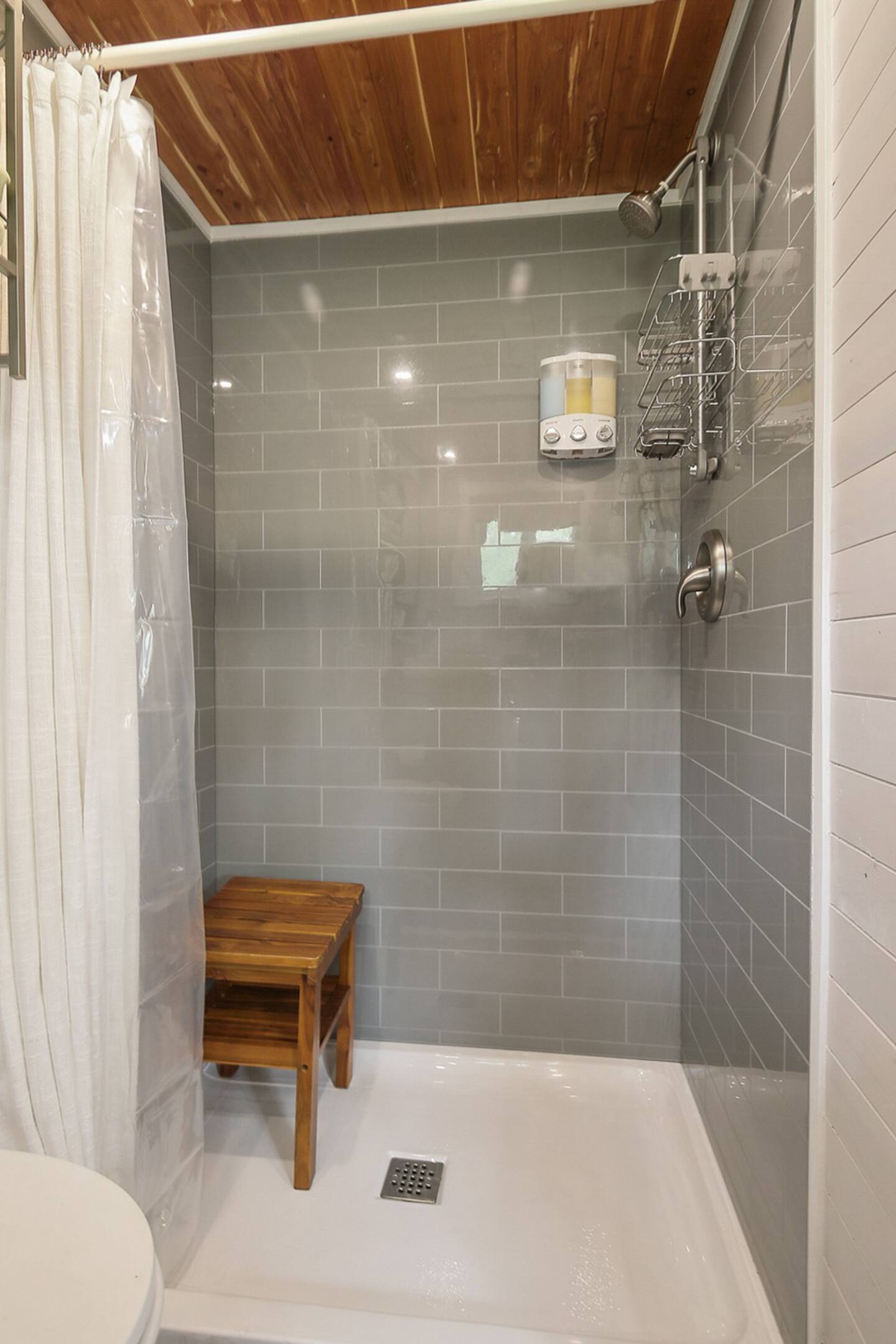 Shower with grey tiles and wood small chair