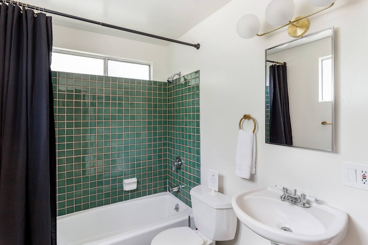 Small green tiles in shower and black curtains