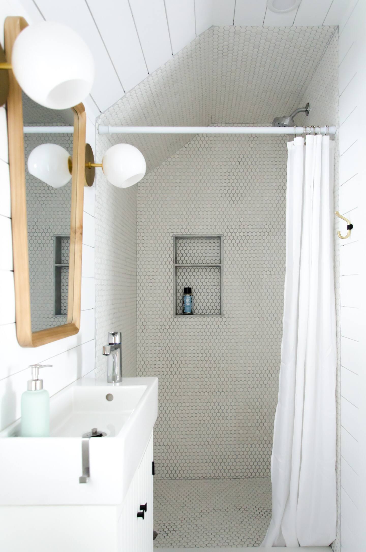 Smile white shower with tiny tiles and a pearl white sink with wooden mirror