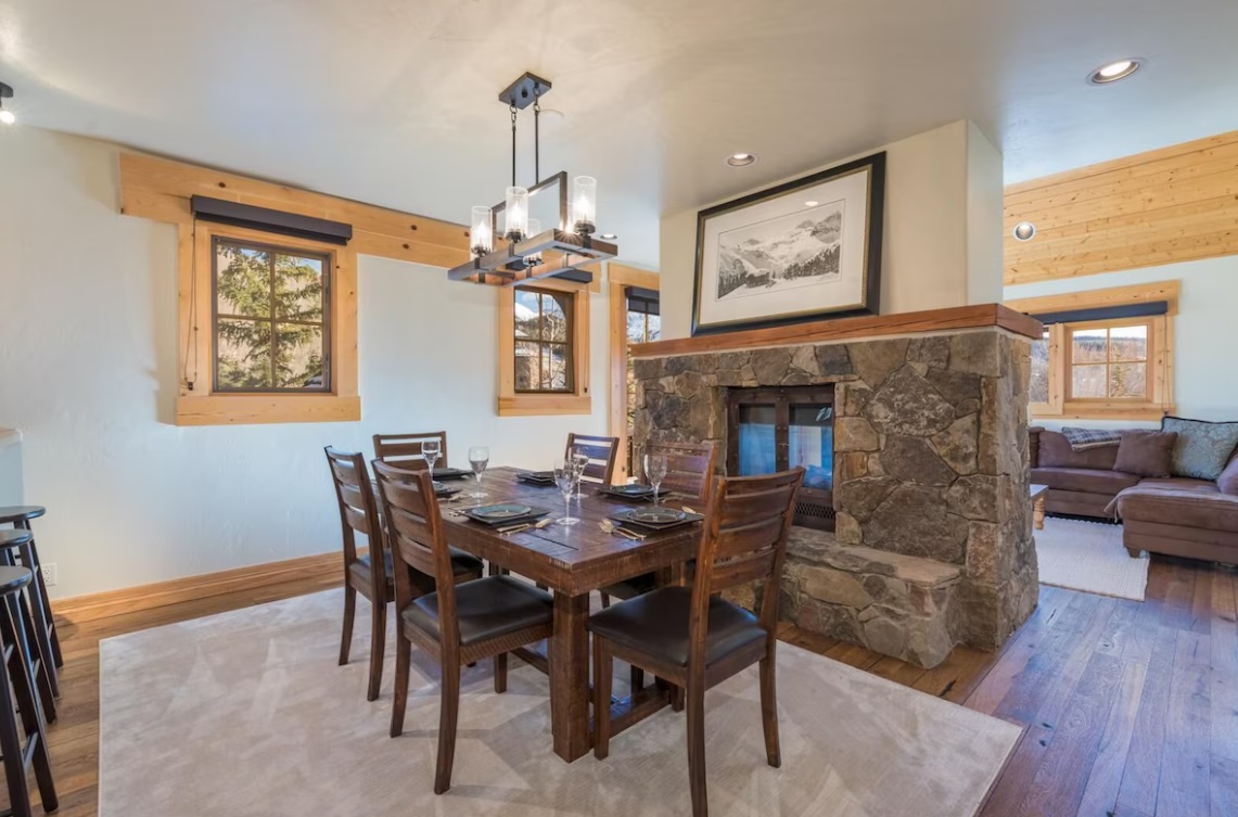Six wooden chairs and table located in front of the great stone fireplace
