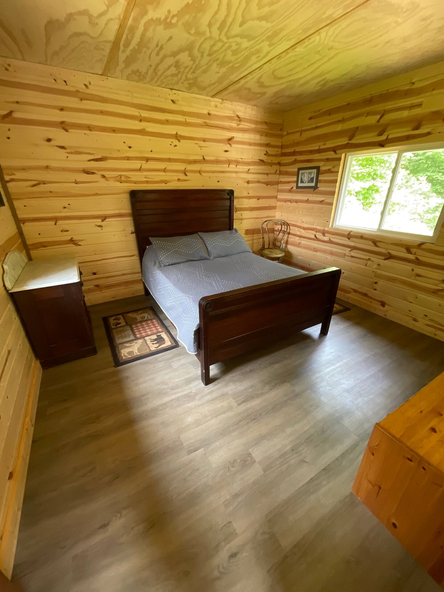 Wooden queen sized bed next to the window