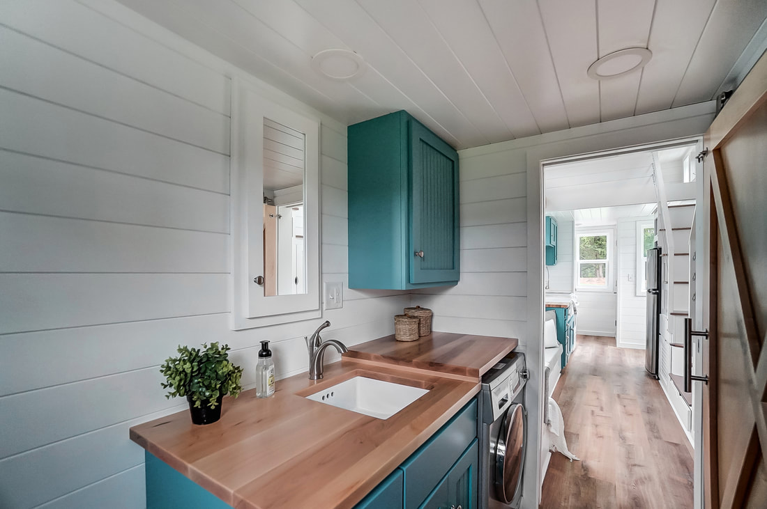 small toilet with teal cabinets and wooden countertop