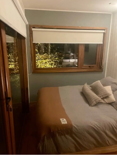 bedroom of a container house, glass door and window next to bed
