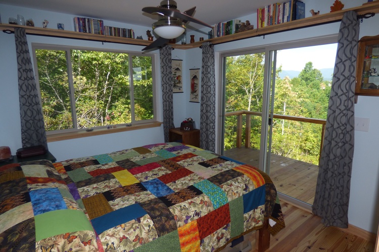 Queen sized bed in master bedroom with colorful blanket on it, with a private terrace