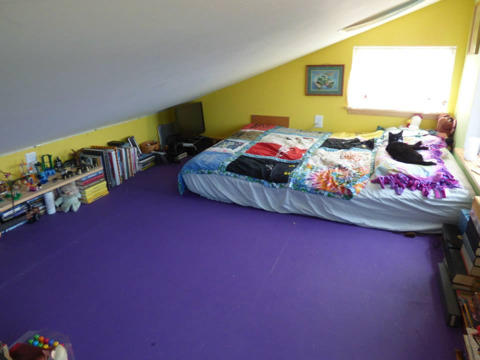 Montessorri style of kids room with yellow walls, purple floor and books on it