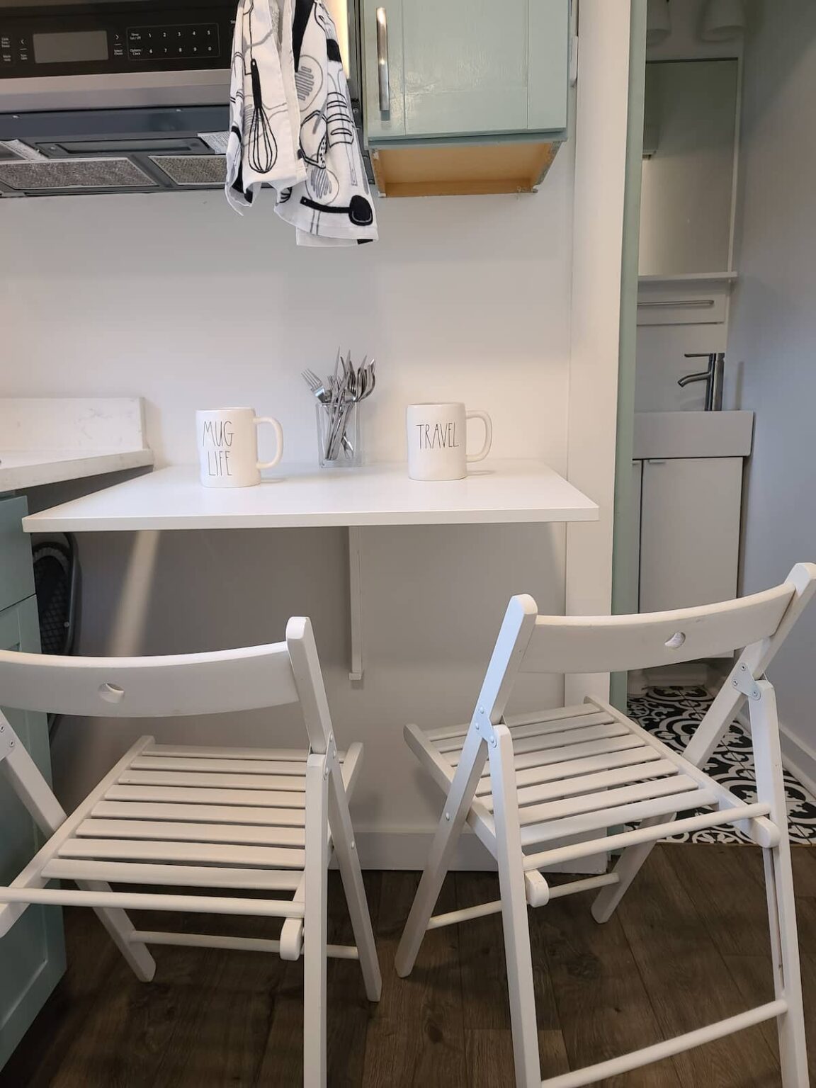 Small dining table with two white wooden chairs in the kitchen