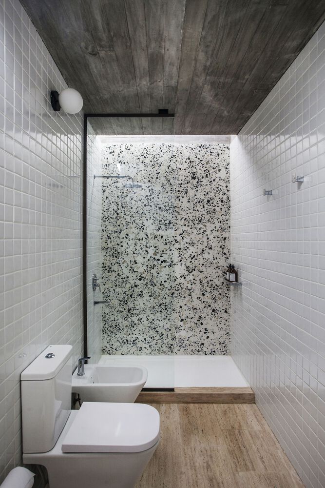 Small shower in this modern home, with wooden floor and colorful black and white tiles in shower