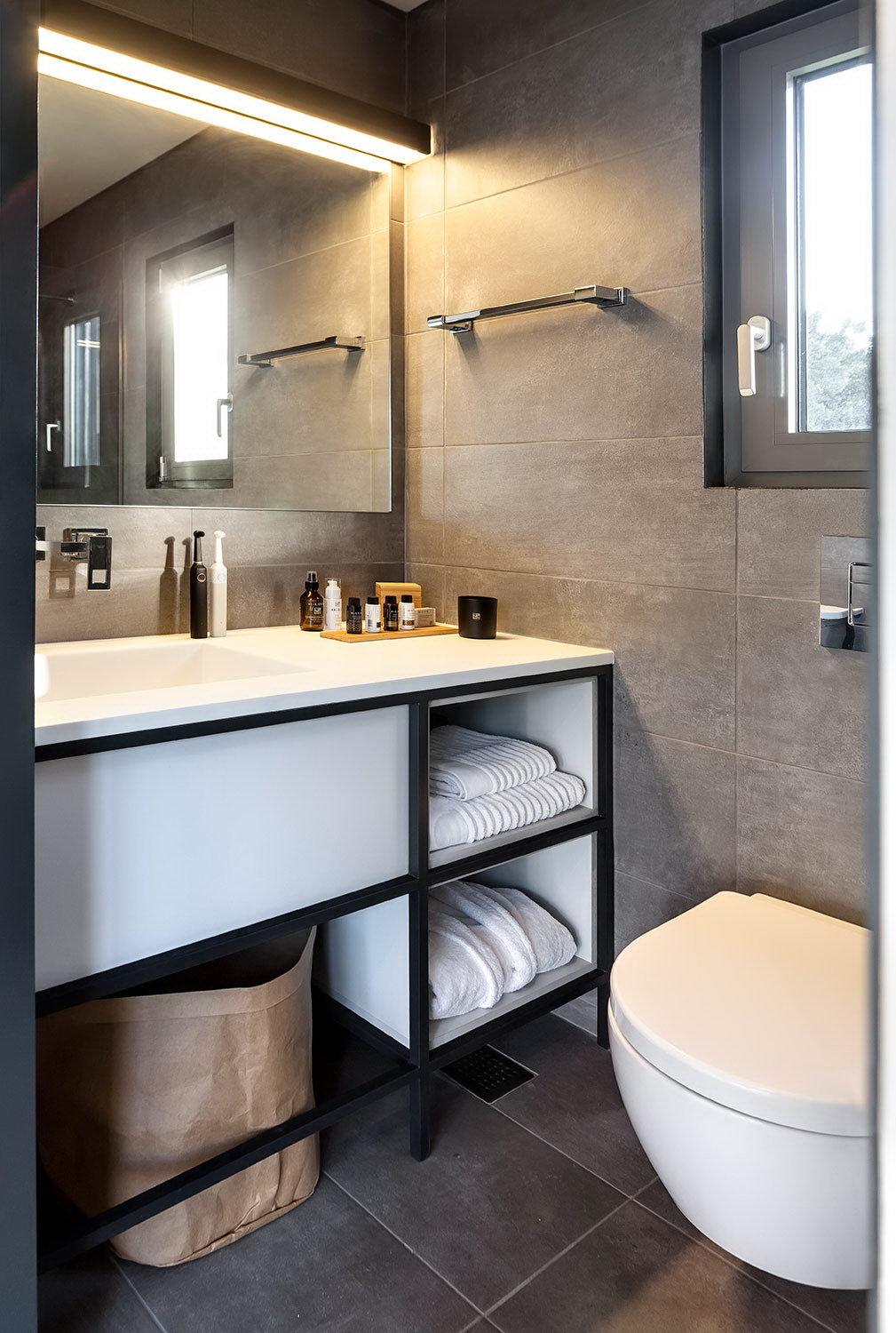 bathroom with black tiles and black and white cabinet and a mirror
