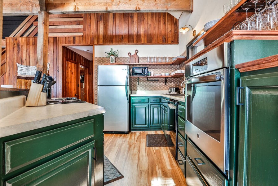 kitchen with dark green cabinetsm white countertops and patterned walls