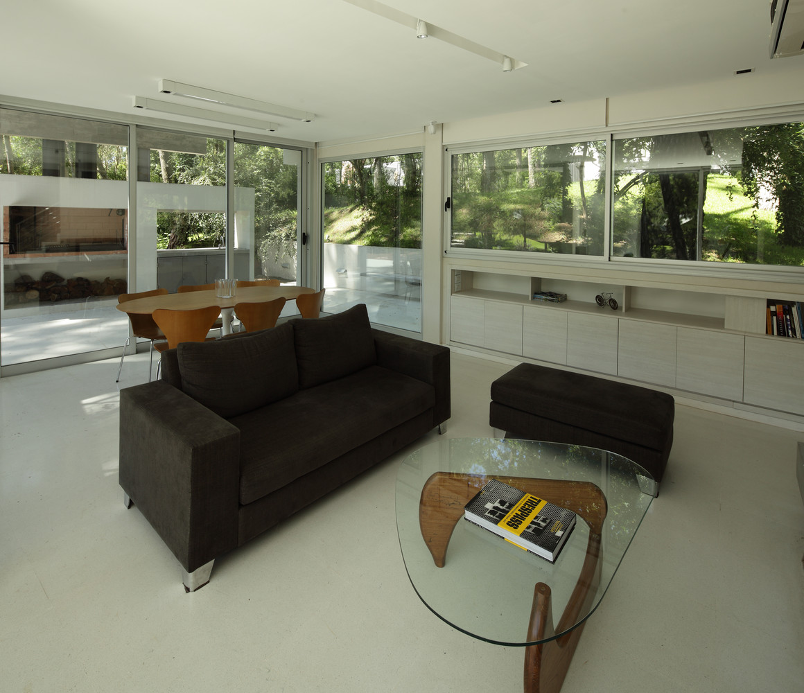 living room with a black couch and a glass table, big windows all around the room