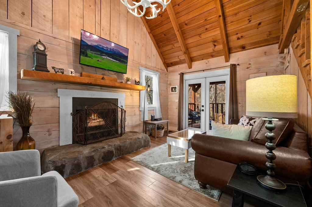 cabin with a brown leather couch and a flat screen tv opposite it with the fireplace under it