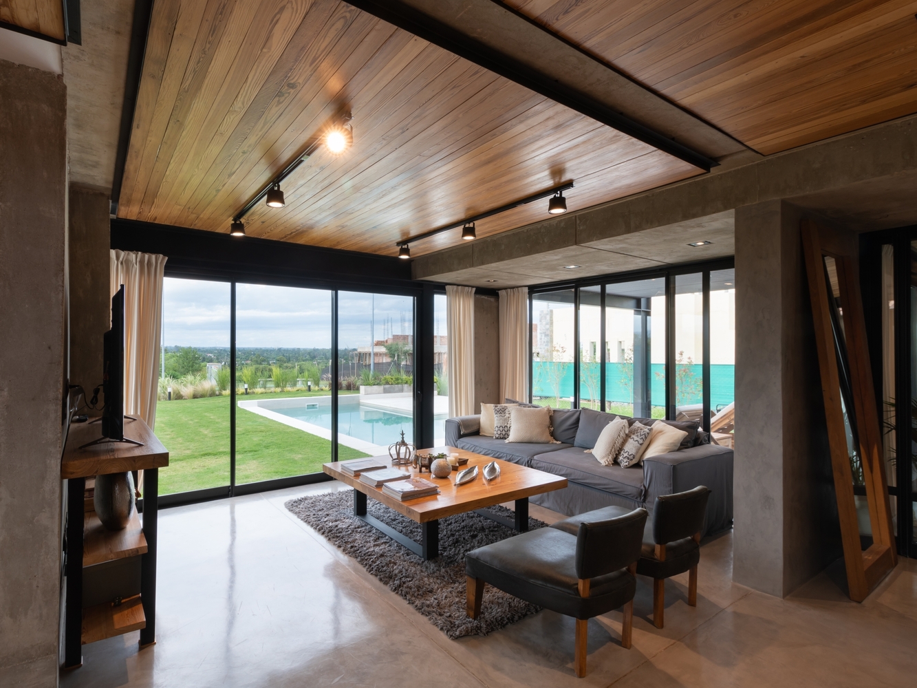 living room with a gray couch, two leather chairs and floor to ceiling windows