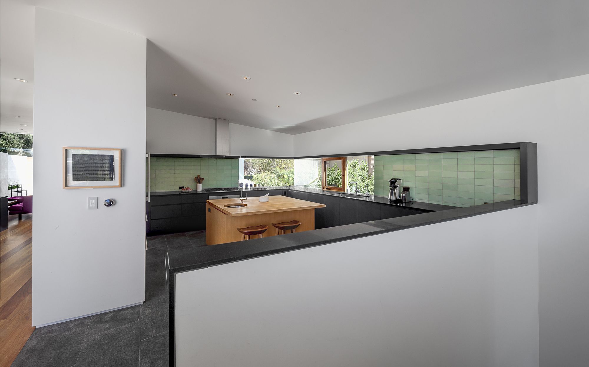 minimalist kitchen of a modern house, brown island surrounded by black cabinets