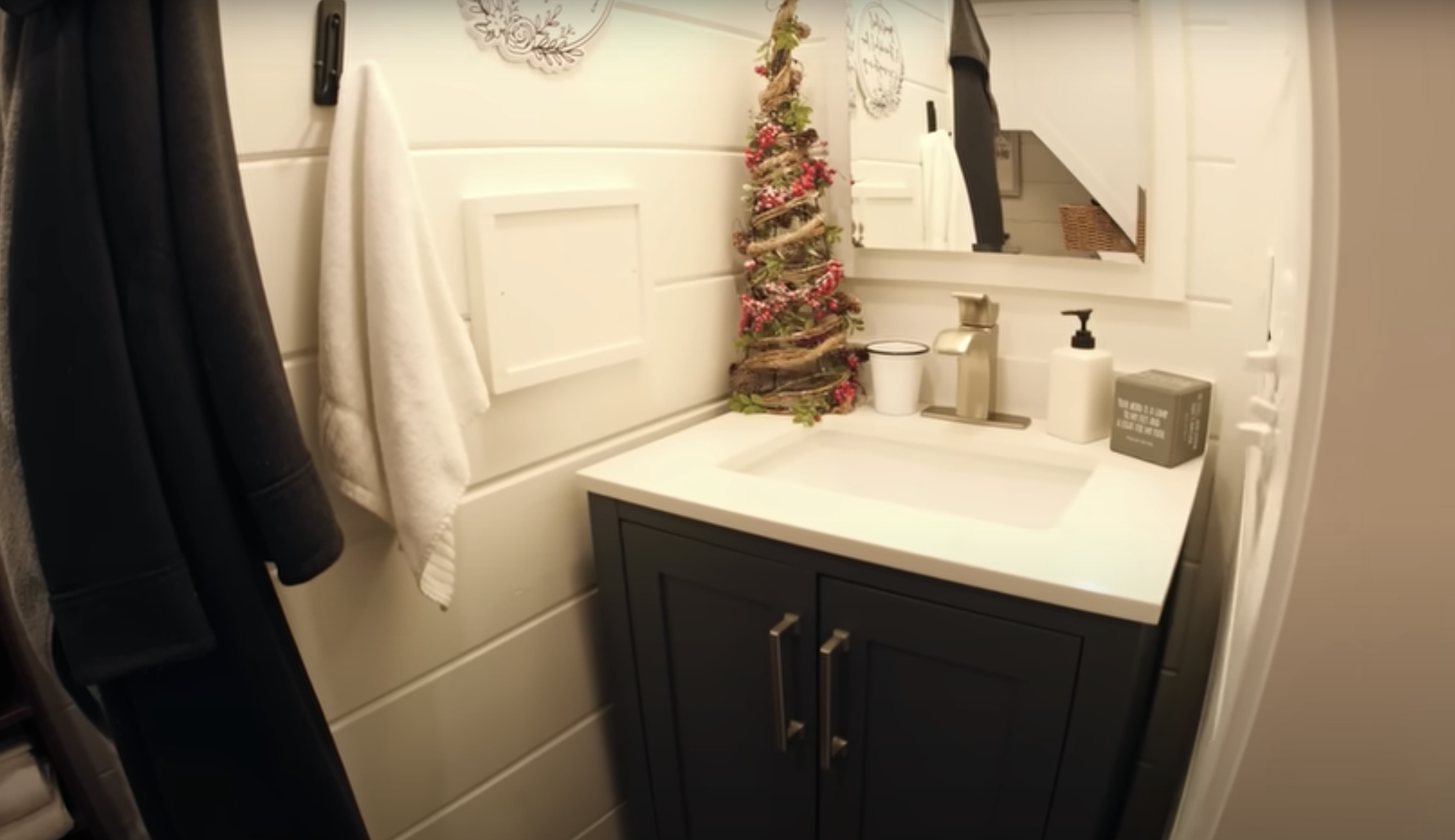 tiny house bathroom with white sink and little Christmas tree on it