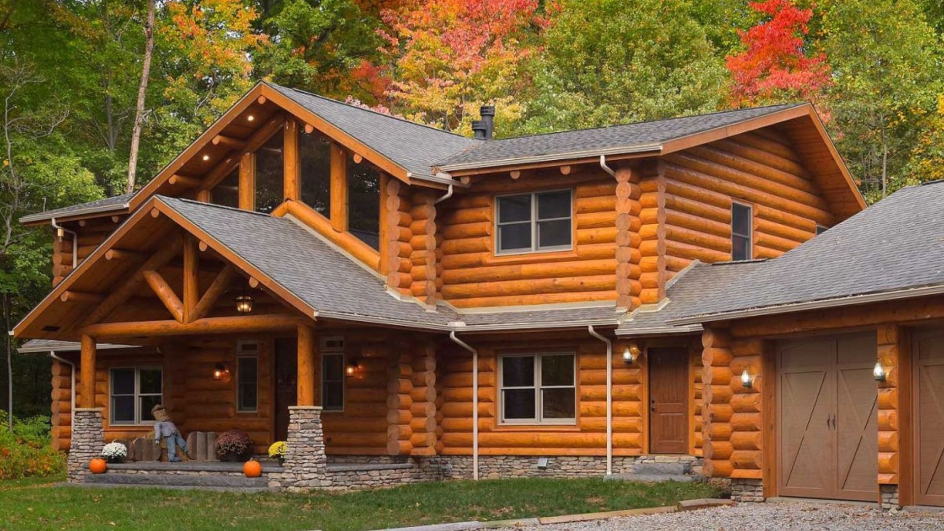 exterior of the log cabin with an adjacent three-car garage, surrounded by trees