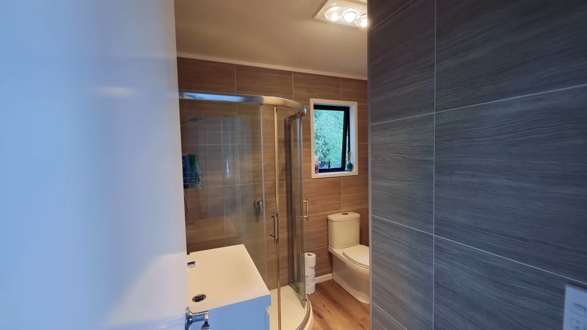 A bathroom with a shower and brown tile