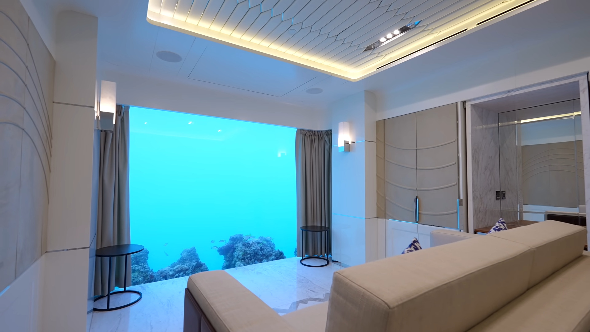 White underwater bedroom with a glass panel showing the ocean