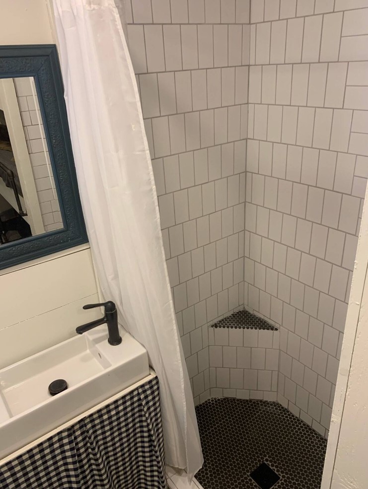 Black and white bathroom with full sized shower and small sink