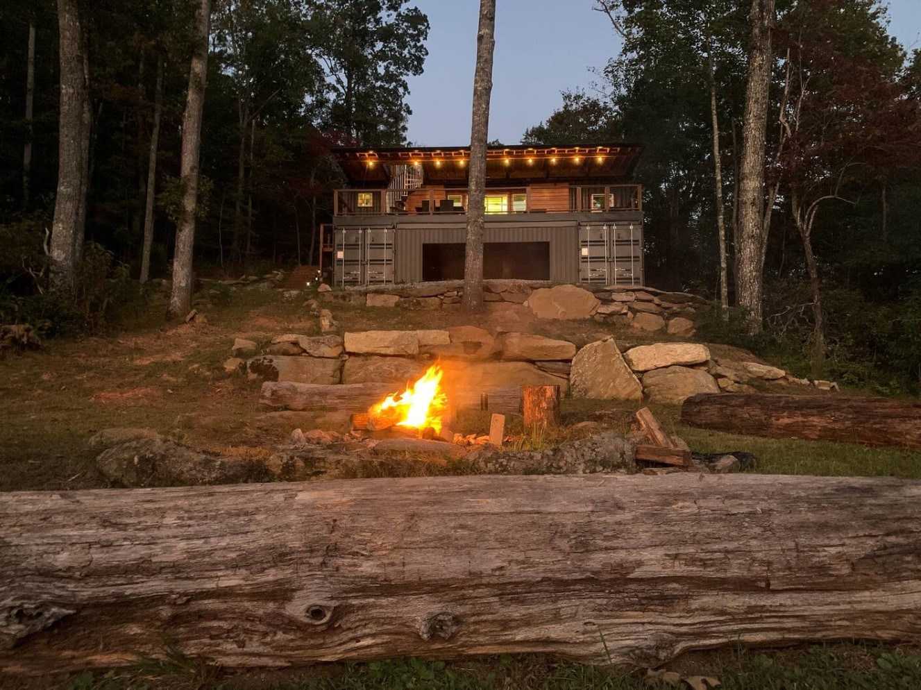 Container cabin in woods with deck and fire place