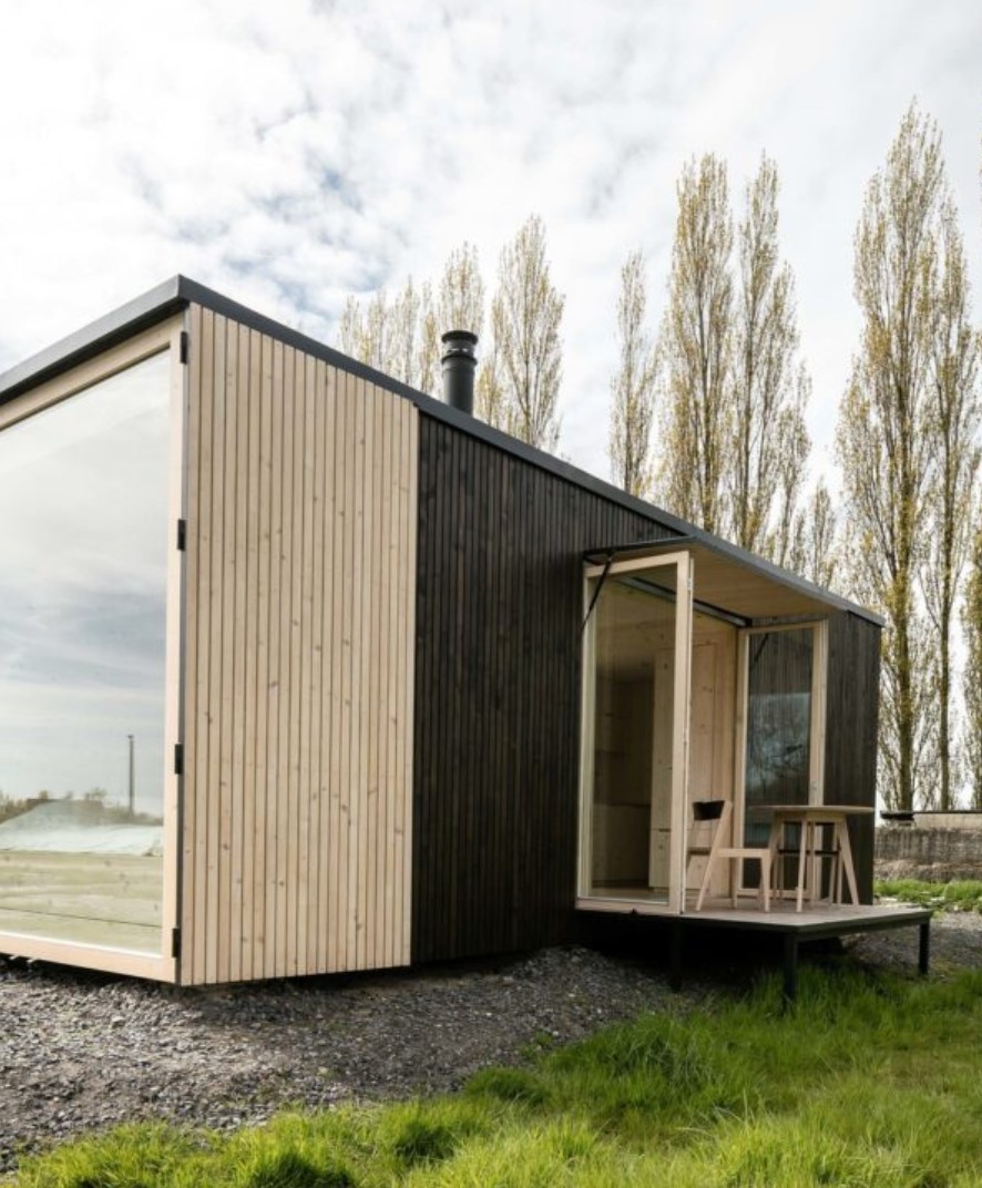 Exterior of a black container home with a deck and a large window