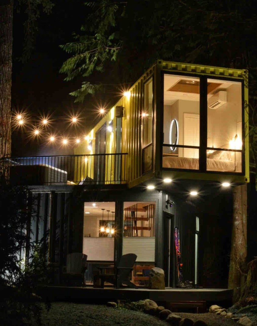 Exterior of two floor container home with large windows and lighting