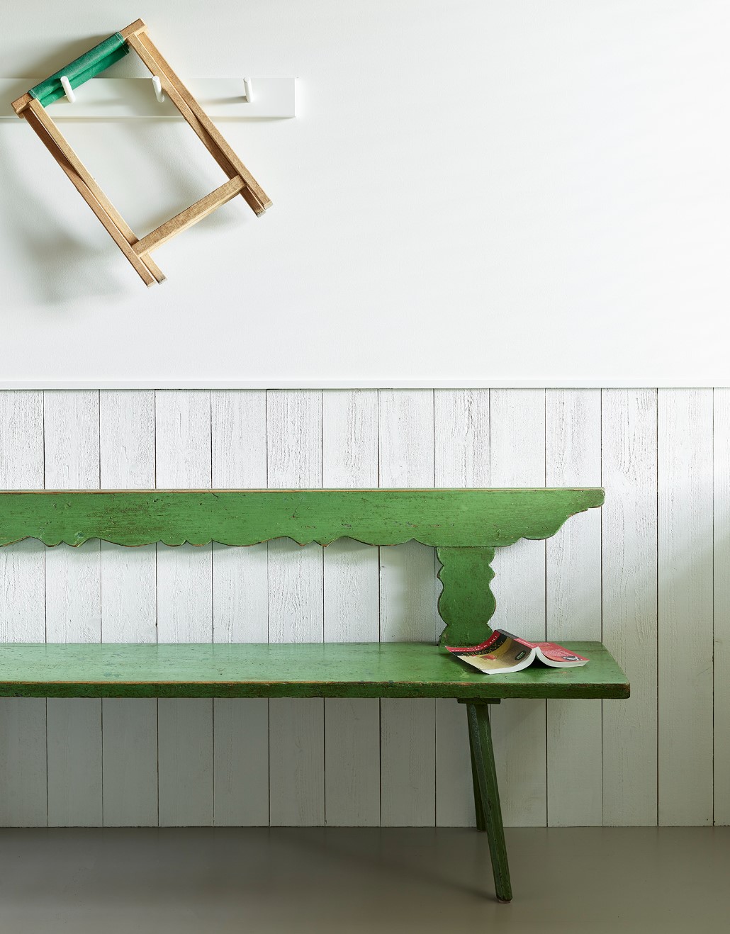 Green bench against a white wall