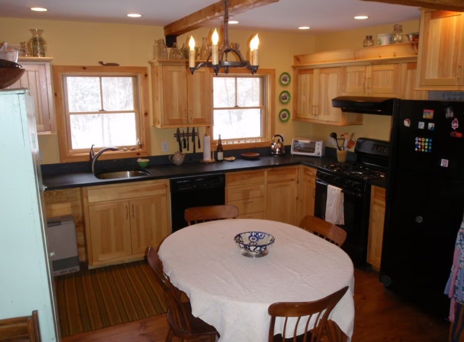 Kitchen in a cabin with a black fridge and a wooden dining table