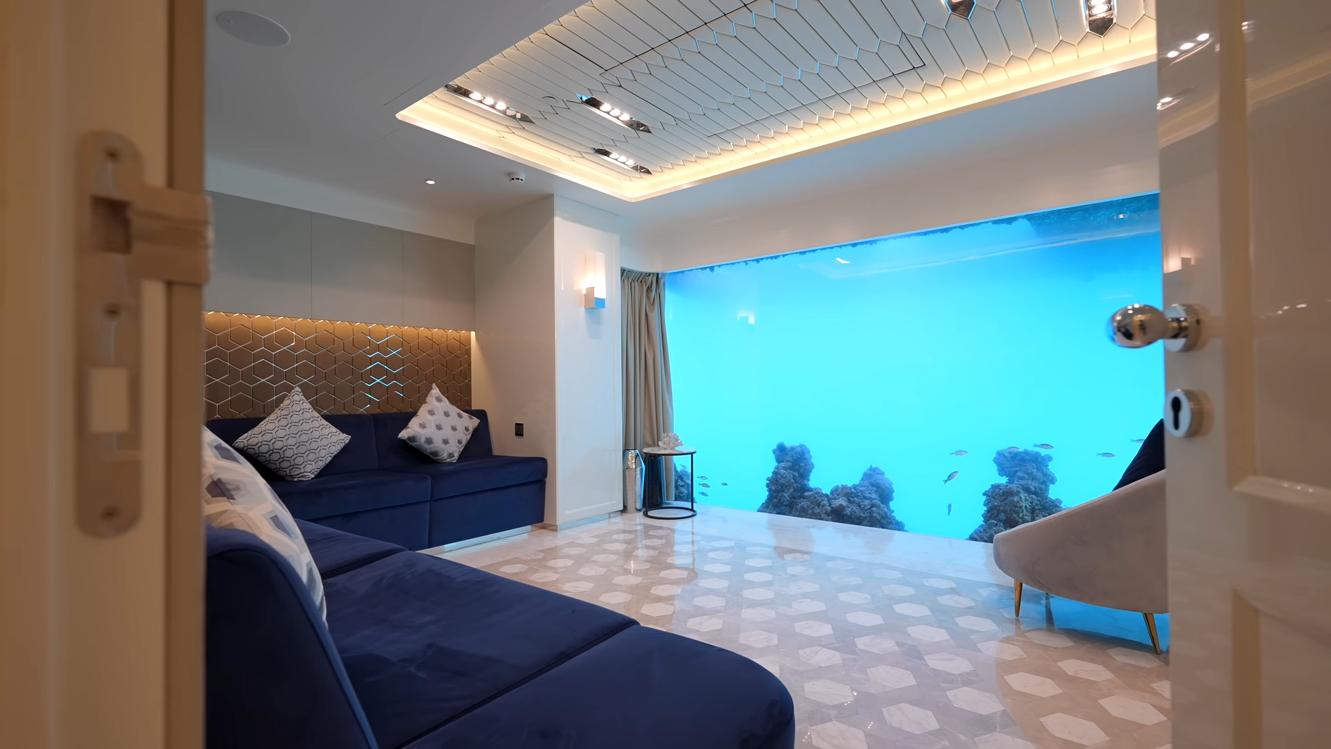 Underwater master bedroom with blue couch and a large glass panel showing the ocean