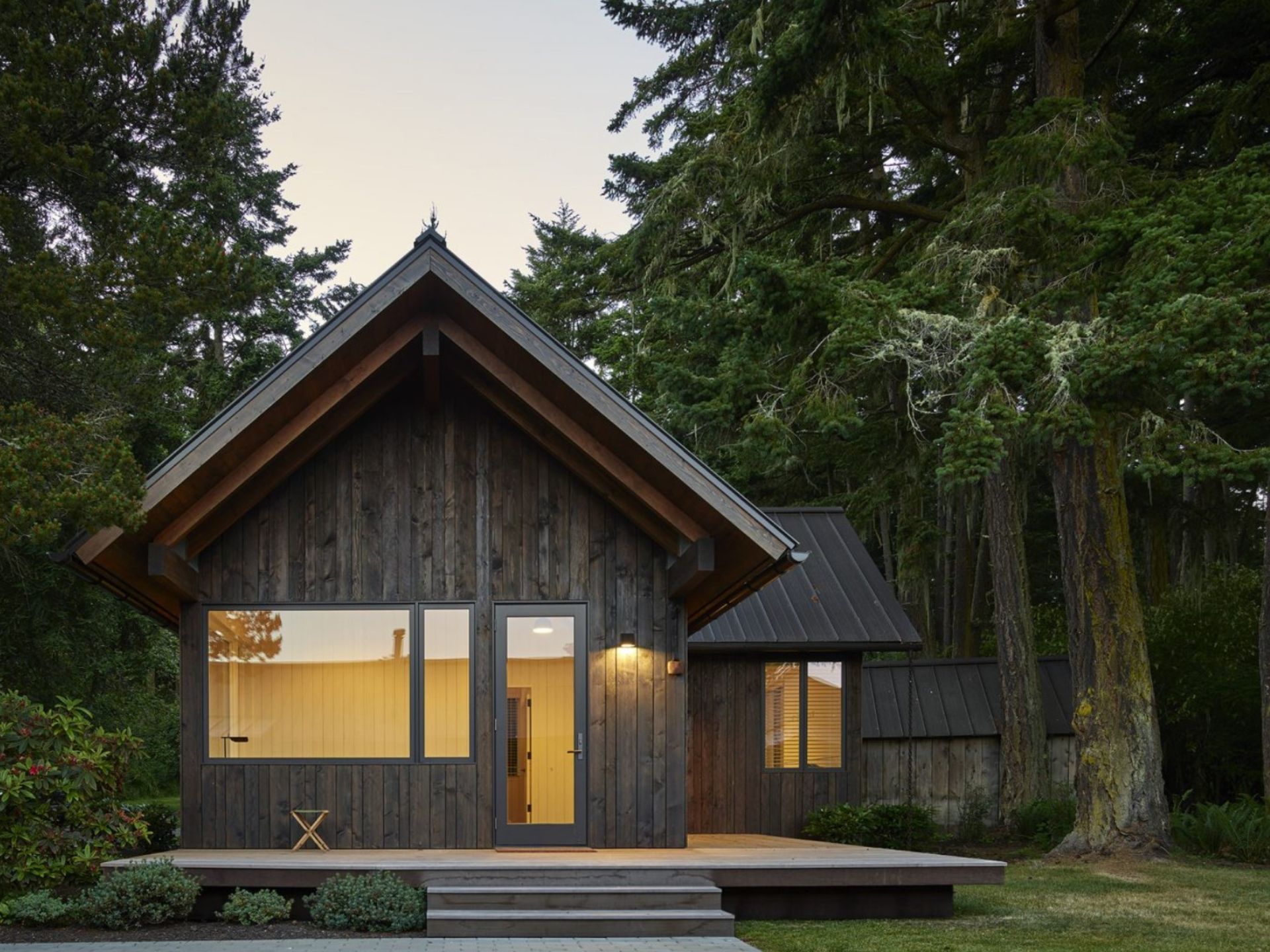 Exterior of a cabin in a forest with lights turned on