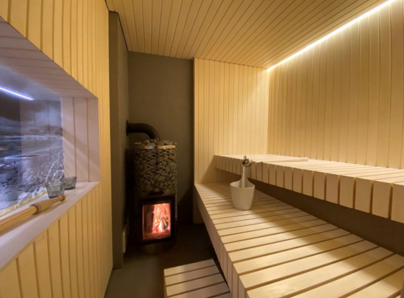 Sauna with white wooden walls and a window