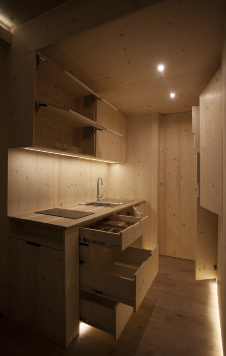 Minimalistic wooden kitchen inside of a container home with LED lights