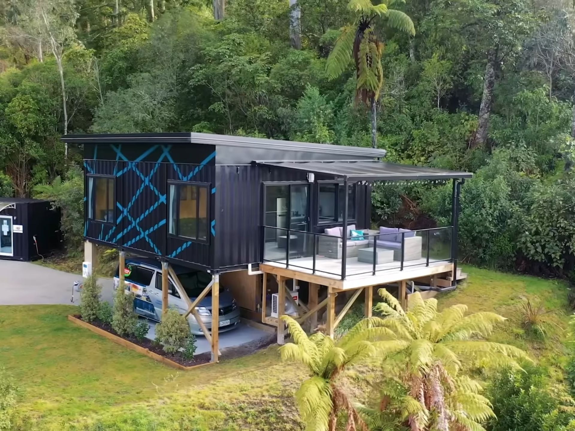 Elevated lakeside container home with a deck and carport