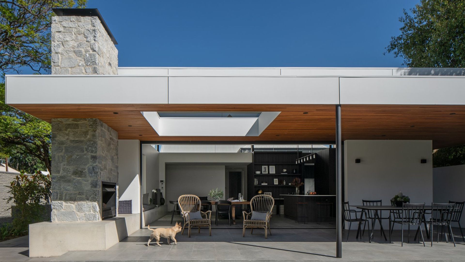 alfresco part of the modern house, visible flat roof, and a giant stone fireplace in the corner