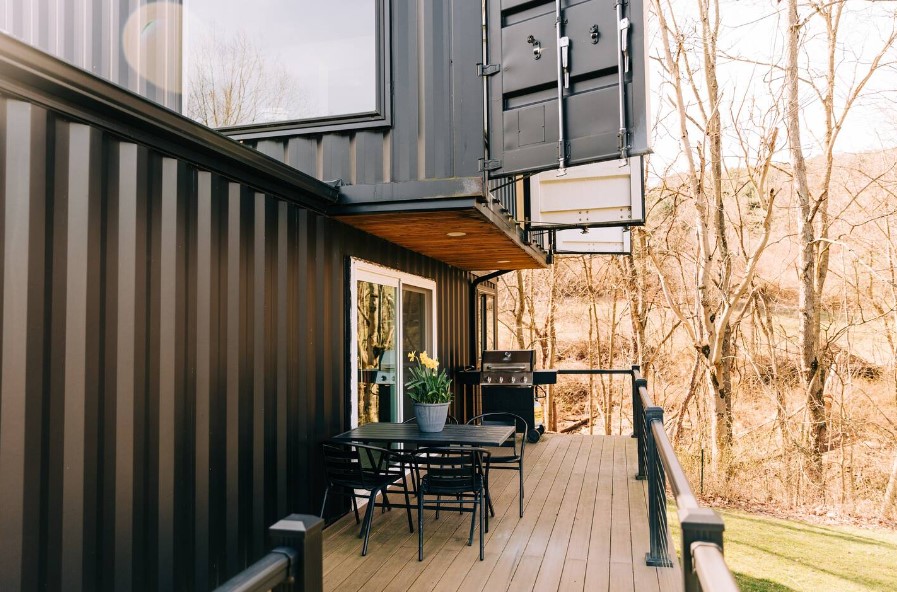 balcony of a container house with a grill and a black table and chairs