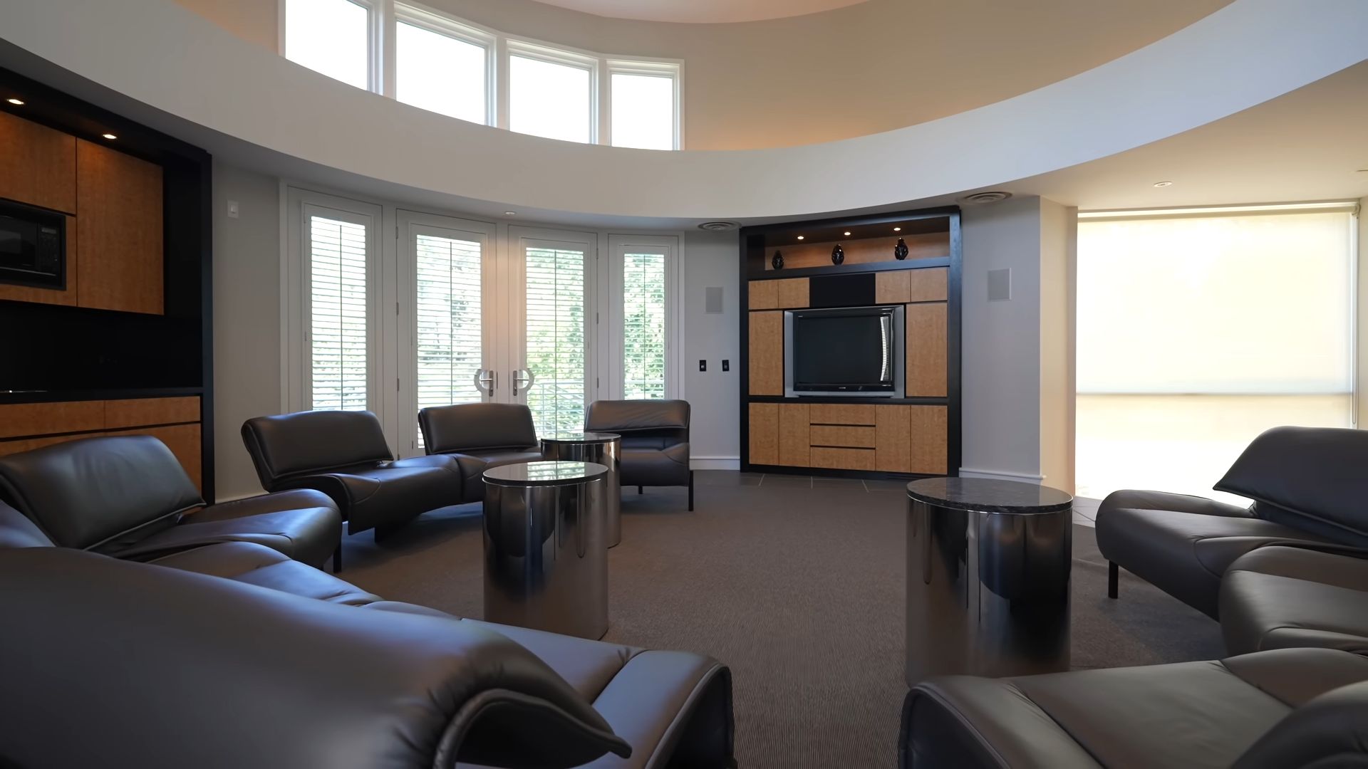 Modern lounge area in basketball pavilion with leather seating, a large TV, and glass doorsModern lounge area in basketball pavilion with leather seating, a large TV, and glass doors