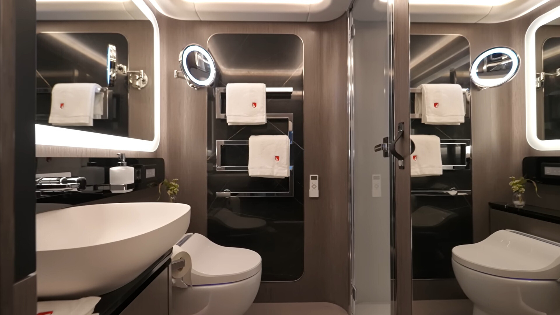 bathroom with a white sink, led lights around a mirror and hangers for towels