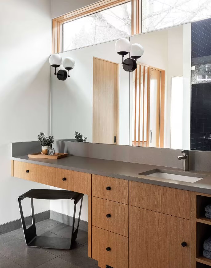 bathroom with brown cabinets and a big mirror and a black chair