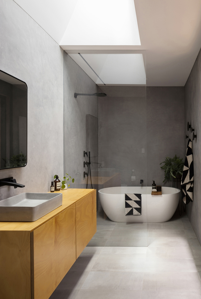 bathroom with gray walls, white bathtub, brown cabinet and a mirror above it