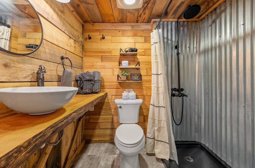 bathroom with a wooden countertop, white sink, round mirror and a white toilet